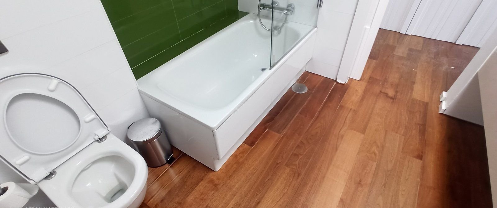 Baño reformado con bañera y suelo de madera