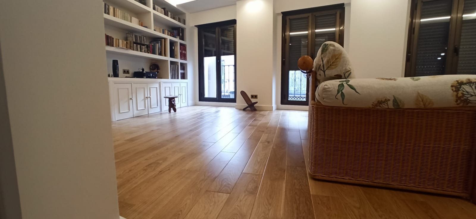 Salón con librería y suelo de madera